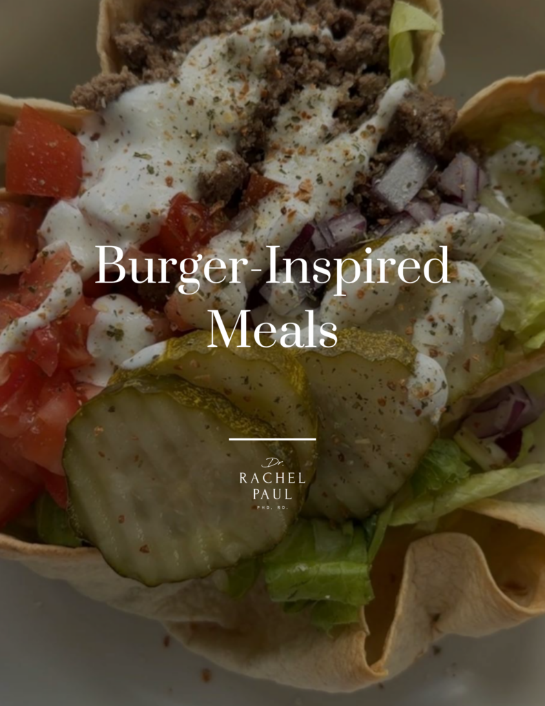 Close-up of a burger-inspired meal featuring sliced pickles, chopped onions, tomatoes, lettuce , and seasoned toppings on a crea